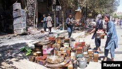 Afghan shopkeepers try to recover items from burning shops after a Taliban attack in Ghazni city, Afghanistan, Aug. 14, 2018.