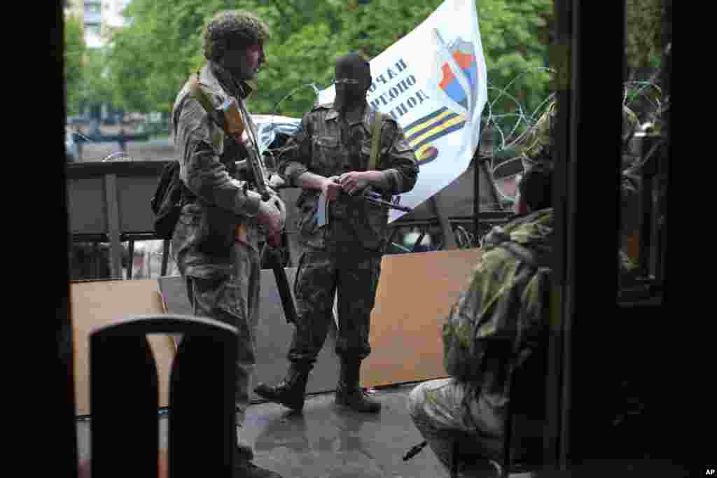 Pro-Russian gunmen in camouflage uniforms guard an entrance of an administration building they seized on Tuesday in Luhansk, one of the largest cities in eastern, Ukraine, Wednesday, April 30, 2014.