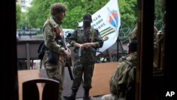 Militantes prorrusos en trajes de camuflaje montan guardia a la entrada de un edificio administrativo en Luhansk.