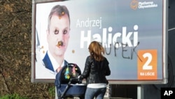 A woman walks past a damaged Civic Platform election poster in Warsaw, Poland, Oct. 26, 2015.