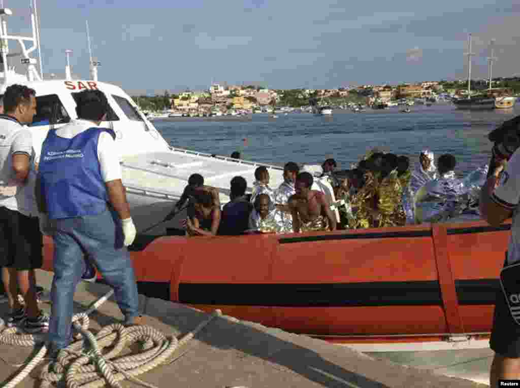 Wahamiaji waliokolewa wakiwasili na boti katika ufukwe wa Lampedusa.