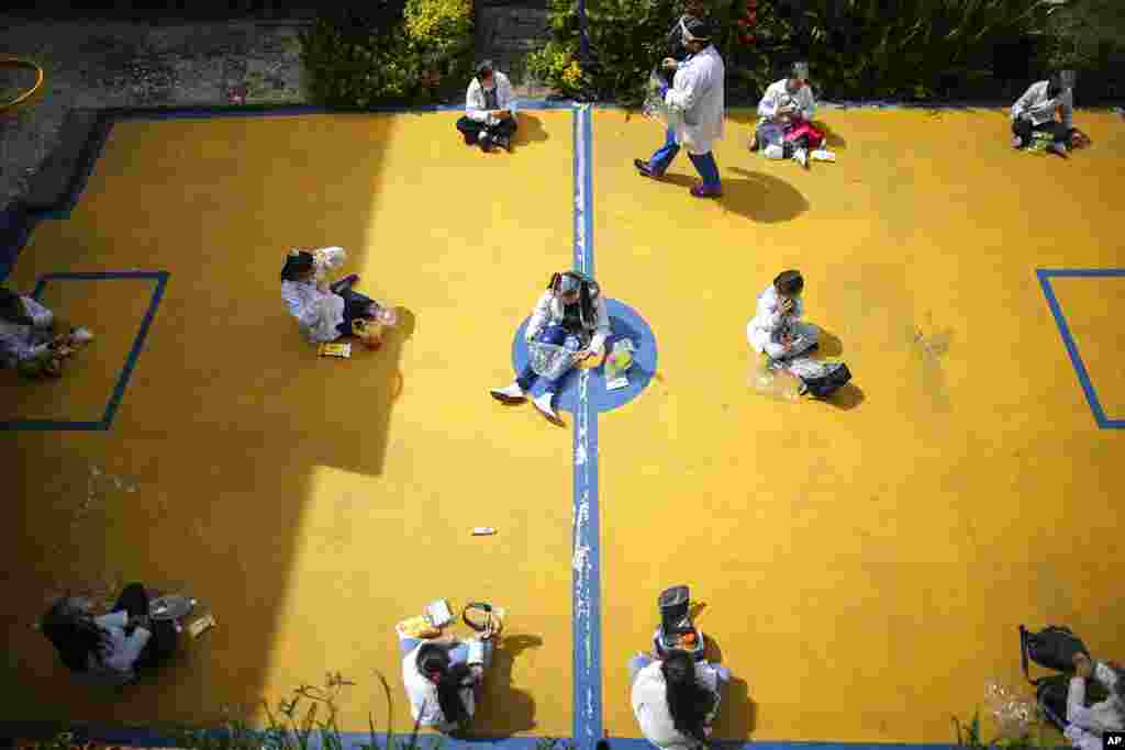 Students wearing COVID-19 protective gear social distance during snack time on their first day back to in-person class since March 2020 at Liceo Lunita, a private school in Chia on the outskirts of Bogota, Colombia.