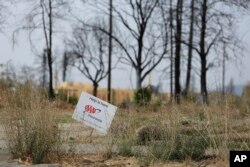 In this photo taken , Aug. 9, 2018, a sign from an insurance company sits at the edge of a Santa Rosa, Calif., property that was destroyed in the deadly October 2017 wildfires.