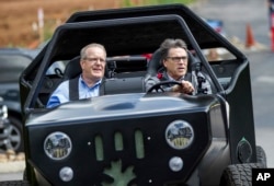 FILE - Energy Secretary Rick Perry, right, drives a 3-D printed vehicle at Oak Ridge National Laboratory's Manufacturing Demonstration Facility with staffer Craig Blue in Knoxville, Tenn., May 22, 2017.