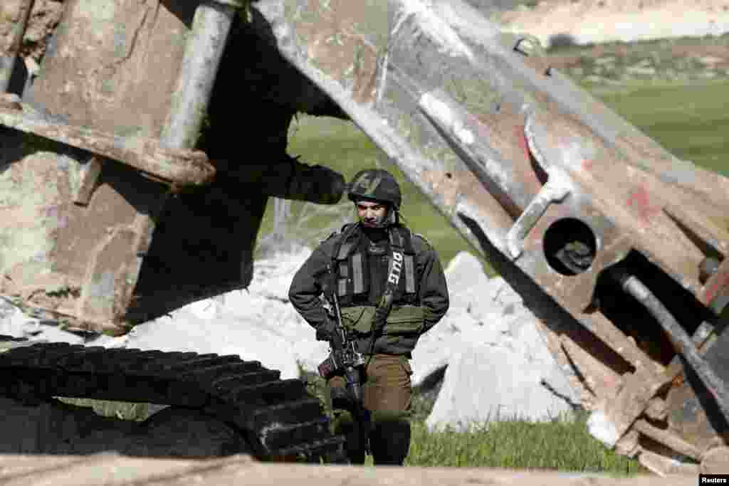 An Israeli soldier stands guard during the demolition of a Palestinian house at the order of the Israeli army, in the West Bank town of Dura, south of Hebron.&nbsp;The owners of the house said they were informed by the Israeli army that the demolition was carried out because they did not have an Israeli-issued construction permit.