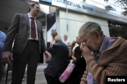 A bank manager explains the situation to pensioners waiting outside a branch of the National Bank of Greece hoping to get their pensions, in Thessaloniki, Greece, June 29, 2015.