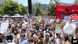 FILE - People hold signs as they participate in the "Families Belong Together: Freedom for Immigrants" march, June 30, 2018, in Los Angeles. 