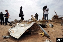 Journalists look at debris at the crash site of the Air Algerie Flight AH 5017 in Mali's Gossi region, west of Gao, July 26, 2014.
