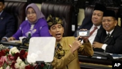 Presiden Joko Widodo, yang mengenakan busana tradisional Nusa Tenggara Barat, menunjukkan layar ponselnya saat menyampaikan pidato pada Sidang Tahunan dalam peringatan ulang tahun ke-74 Republik Indonesia.(Foto: AP)