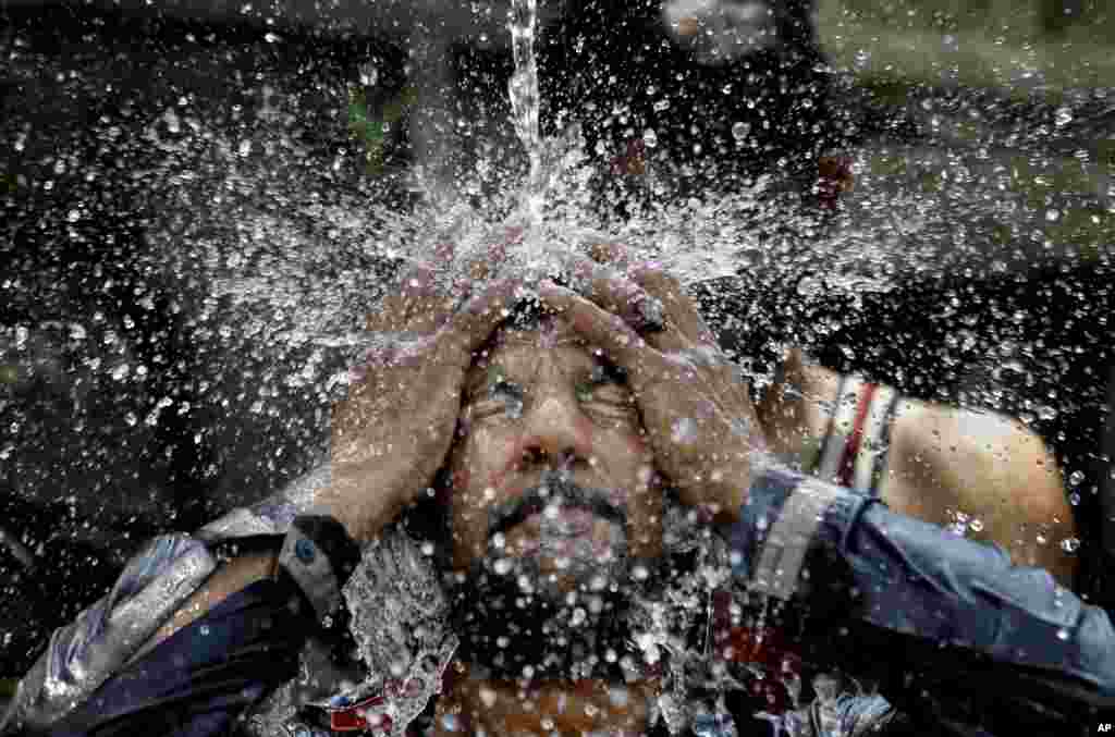 A man cools himself off under a water supply to beat the heat during the holy fasting month of Ramadan, in Islamabad, Pakistan.