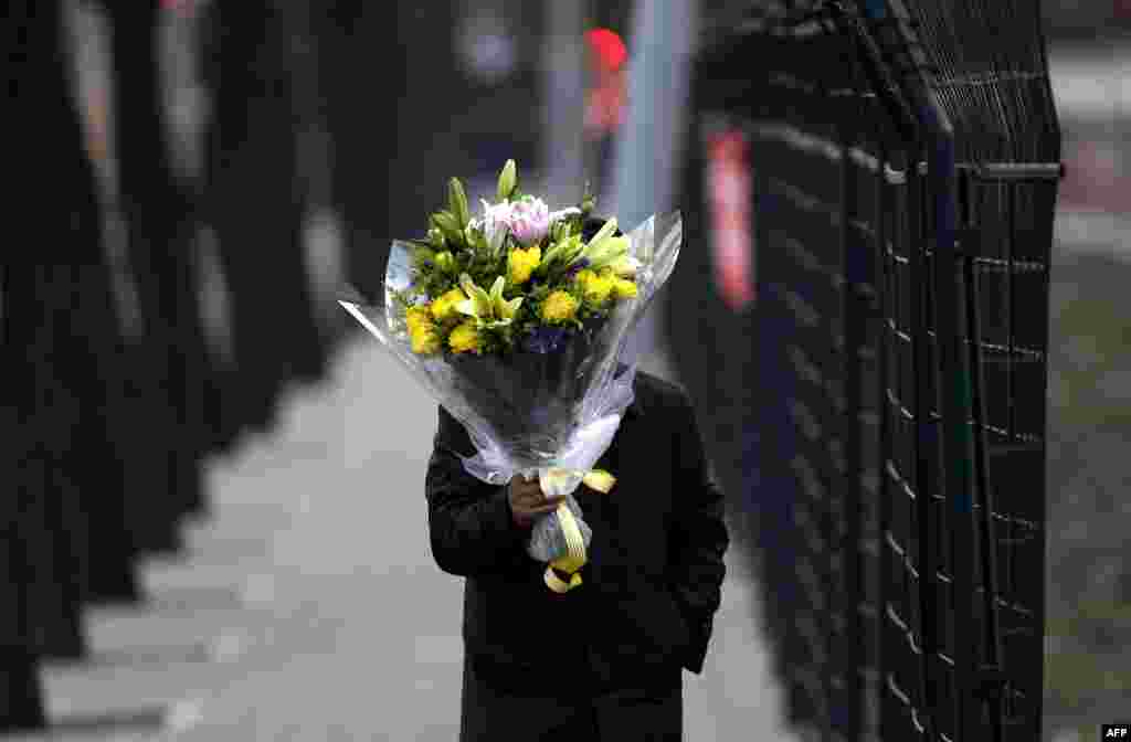 Một người dùng bó hoa che mặt để tránh ống kính nhà báo trong khi mang hoa đến viếng đại sứ quán Bắc Triều Tiên. 19 tháng 12.
