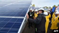Visitors examine solar panels during the official opening ceremony of the new one-megawatt power plant next to the now sealed Chernobyl nuclear plant, in Chernobyl, Ukraine, Oct. 5, 2018.