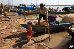 FILE - A man and grandchild prepares fishing nets at the Kbal Chroy village on the Mekong River bank near Phnom Penh, Cambodia, May 17, 2018.