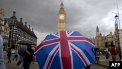 یک عابر زیر چتری با تصویر پرچم بریتانیا، جلوی ساعت «بیگ بن» بعد از اعلام نتایج رأی گیری «برگزیت» ۲۵ ژوئن ۲۰۱۶