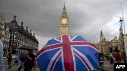 FILE - A pedestrian shelters from the rain beneath a Union Jack-themed umbrella near the Big Ben clock face and the Elizabeth Tower at the Houses of Parliament in central London, following the pro-Brexit result of the UK's EU referendum vote, June 25, 2016.
