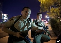 Police officers advise people to take cover near the scene of a shooting near the Mandalay Bay resort and casino on the Las Vegas Strip, Sunday, Oct. 1, 2017, in Las Vegas.