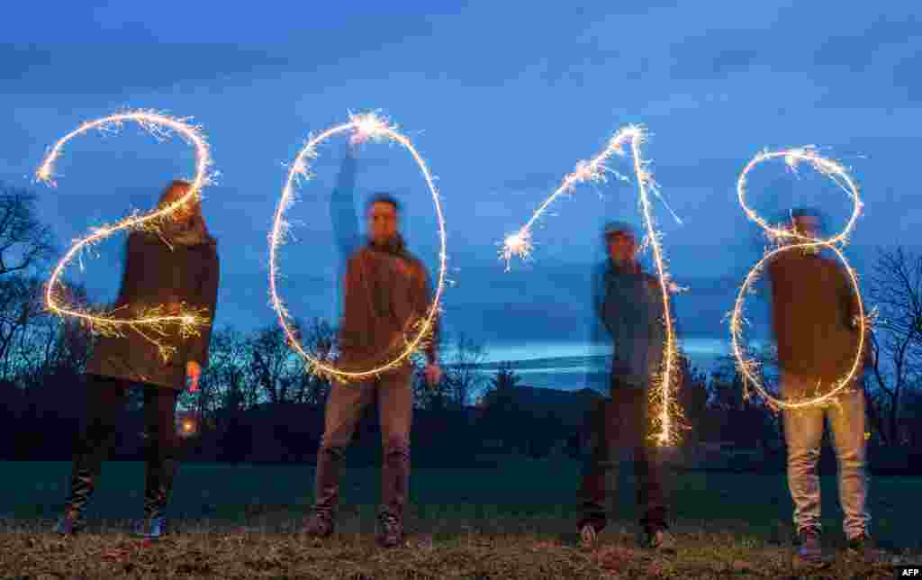 Illustration taken with a long time exposure on December 27, 2017 in Sieversdorf, eastern Germany, shows four people drawing the year "2018" with sparklers.