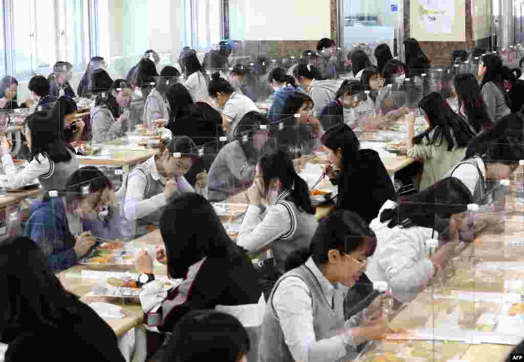 Students eat lunch at tables with protective barriers as a preventative measure against the COVID-19 at a high school in Daejeon, South Korea.