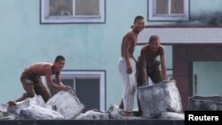 FILE - North Korean men look up as they work along the banks of the Yalu River near the North Korean town of Sinuiju, opposite the Chinese border city of Dandong. North Korean migrant workers often work long hours in difficult and sometimes dangerous jobs