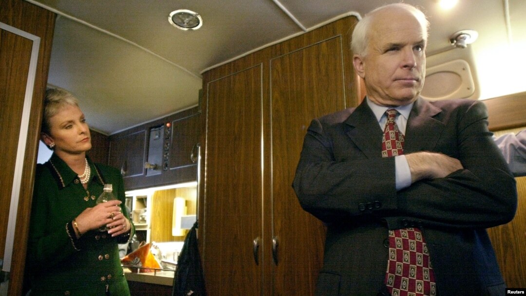Republican presidential candidate Arizona Senator John McCain listens to advice from his campaign staff onboard his bus as his wife, Cindy, looks on near Concord, New Hampshire, Jan. 25, 2000.