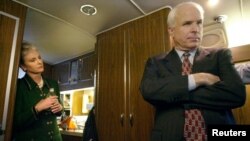Republican presidential candidate Arizona Senator John McCain listens to advice from his campaign staff onboard his bus as his wife, Cindy, looks on near Concord, New Hampshire, Jan. 25, 2000.
