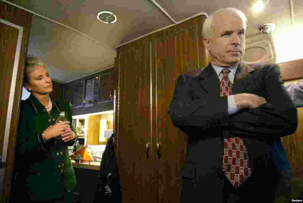 Republican presidential candidate Arizona Senator John McCain (R) listens to advice from his campaign staff onboard his bus as his wife Cindy (L) looks on near Concord, New Hampshire, Jan. 25.