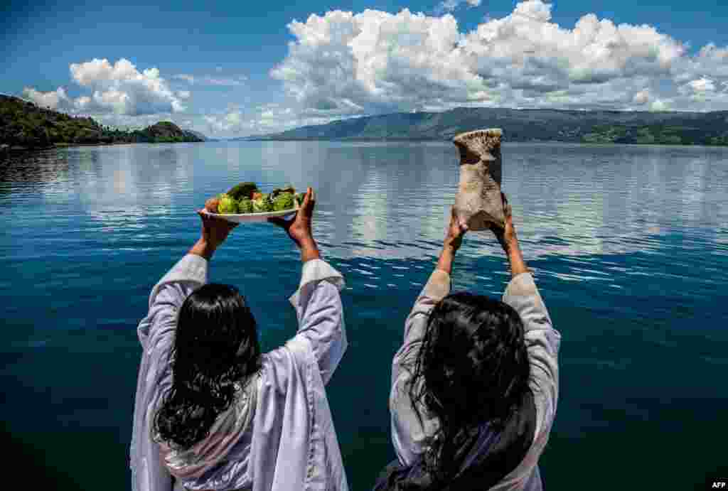اعضای خانواده های قربانیان قایق واژکون شده در دریاچه تابو اندونزی به رسمی دیرین خیرات اموات خود را نثار آب می کنند. &nbsp;