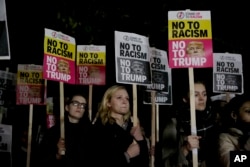 People hold placards as they take part in an anti-racism protest against President-elect Donald Trump winning the American election, outside the U.S. embassy in London, Nov. 9, 2016.