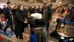 French journalist Ursula Gauthier, a reporter in China for the French news magazine L'Obs, second from left, walks through Bejing Capital International Airport in Beijing, Thursday, Dec. 31, 2015.