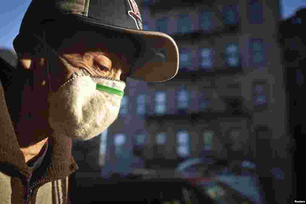 A man wearing a respirator walks past an apartment building where a child was taken the the hospital to be tested for Ebola in the Bronx, New York, Oct. 27, 2014.