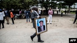 Un homme avec un portrait d'Etienne Tshisekedi devant Notre-Dame de Kinshasa , le 1er février 2019 à Kinshasa (Photo JOHN WESSELS / AFP)