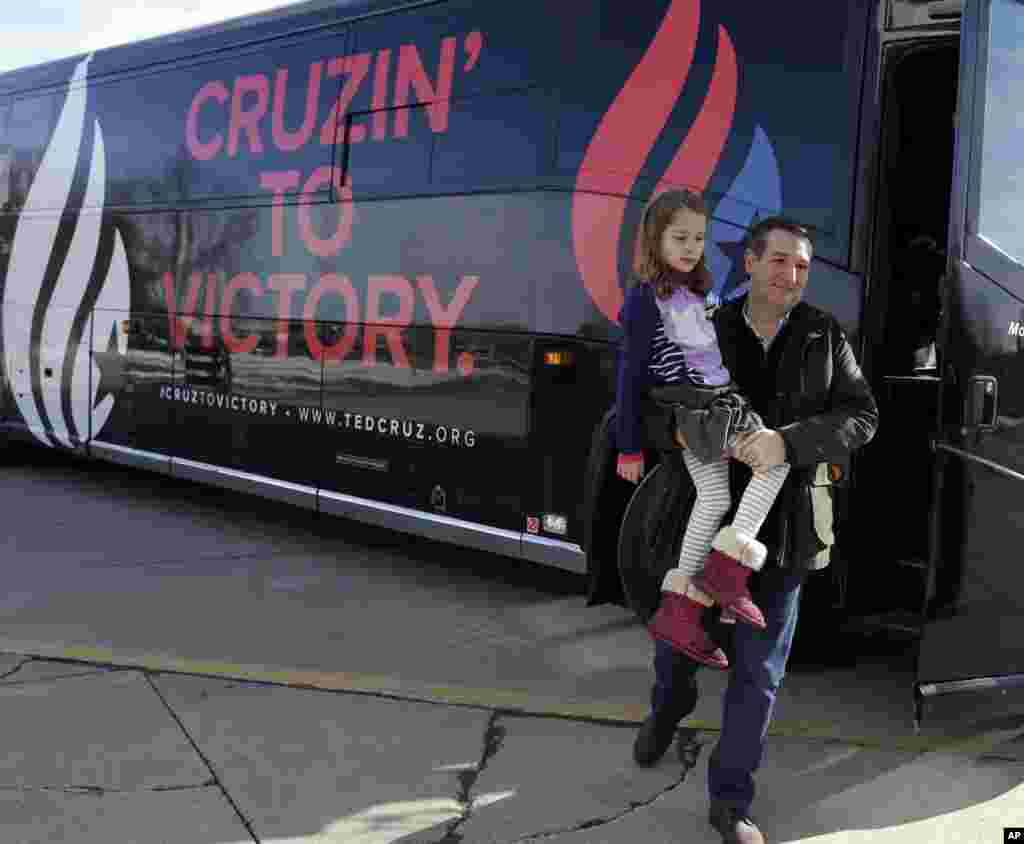 Republican presidential candidate, Sen. Ted Cruz, R-Texas, carries his daughter Caroline, 7, as he arrives at Green County Community Center for a campaign event in Jefferson, Iowa, Feb. 1, 2016.