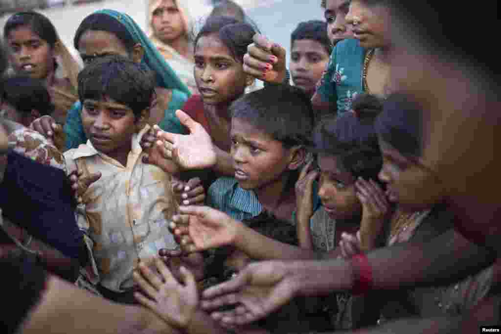 Children displaced by the rising waters of the river Yamuna wait to receive free food distributed by volunteers outside makeshift tents at a roadside camp in New Delhi, India. 