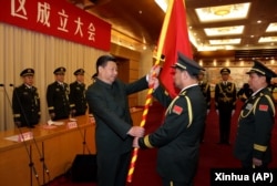 中國國家主席習近平（左前）在北京舉行的中國人民解放軍戰區成立大會上向五大戰區授予軍旗。（2016年2月1日）