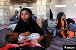 A Yemeni refugee cradles a baby in a temporary shelter in Bosasso, a port town in Somalia's Puntland, April 17, 2015.