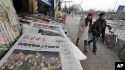 A Chinese couple walks past a newspaper front page showing Egyptians celebrating and title 'Mubarak hands over power' at a newsstand in Beijing, China, February 12, 2011