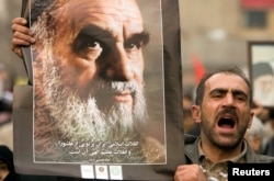 FILE - A man holds a picture of Ayatollah Ruhollah Khomeini, founder of the Islamic Republic as government supporters protest against opposition demonstrations during the holy day of Ashura, in Tehran, Dec. 30 2009.