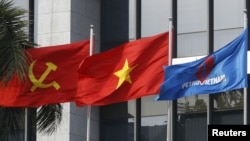 FILE PHOTO: Flag of PetroVietnam flutters next to Vietnamese national flag and Communist Party flag in front of the headquarters of PetroVietnam in Hanoi Jan. 11, 2016. 