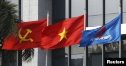 FILE PHOTO: Flag of PetroVietnam flutters next to Vietnamese national flag and Communist Party flag in front of the headquarters of PetroVietnam in Hanoi Jan. 11, 2016.