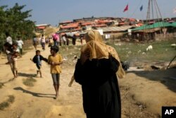 A Rohingya Muslim woman covers her face from the afternoon dust and heat as she walks through Jamtoli refugee camp, Nov. 27, 2017, in Bangladesh. Since late August, more than 630,000 Rohingya have fled Myanmar's Rakhine state into neighboring Bangladesh.