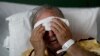 FILE - A flu patient places a cold compress on his forehead at Upson Regional Medical Center in Thomaston, Ga., Feb. 9, 2018.