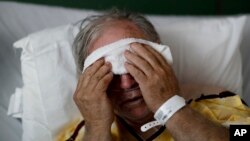 FILE - A flu patient places a cold compress on his forehead at Upson Regional Medical Center in Thomaston, Ga., Feb. 9, 2018.