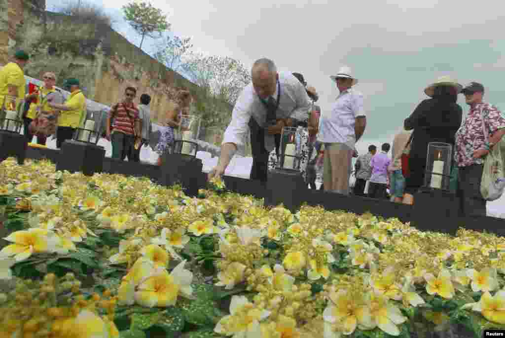 Người đến dự lễ kỷ niệm đặt hoa v&agrave;o hồ tưởng niệm c&aacute;c nạn nh&acirc;n vụ đặt bom