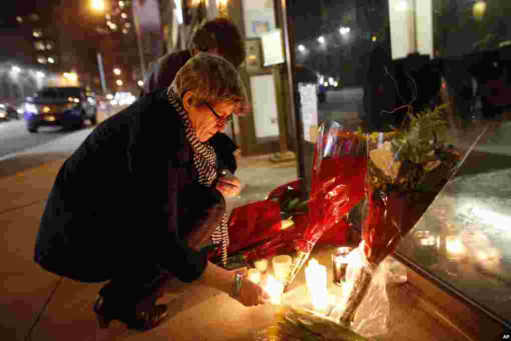 Australian native Kate Gilmore, who now resides in New York, lights candles at a makeshift memorial for South African leader Nelson Mandela outside the South African consulate, Dec. 5, 2013, in New York. 