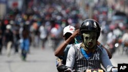 Yon manifestan kji sou yon moto ak yon mask nan figi l. Foto Achiv: Pòtoprends, Ayiti