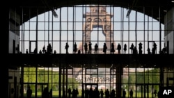 Para turis mengikuti presentasi di "Grand Palais Ephemere" dengan Menara Eiffel di latar belakang di Paris, Perancis, 9 Juni 2021 (foto: ilustrasi). 
