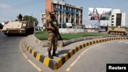 An army soldier stands guard on a road leading to a polling station during a re-polling for the general elections in Karachi, May 19, 2013. 