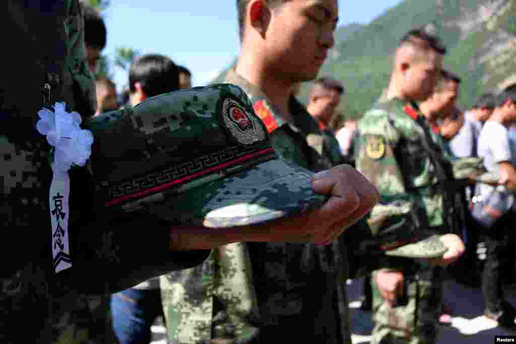 Rescuers and residents observe a moment of silence as they attend a public mourning ceremony for the victims of a landslide in the village of Xinmo, Mao County, Sichuan Province, China.