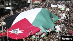 Protesters from Jordanian opposition parties carry a giant national flag while shouting anti-government slogans during a demonstration against what they say are worsening economic conditions, after Friday prayers in Amman February 25, 2011. The protests i