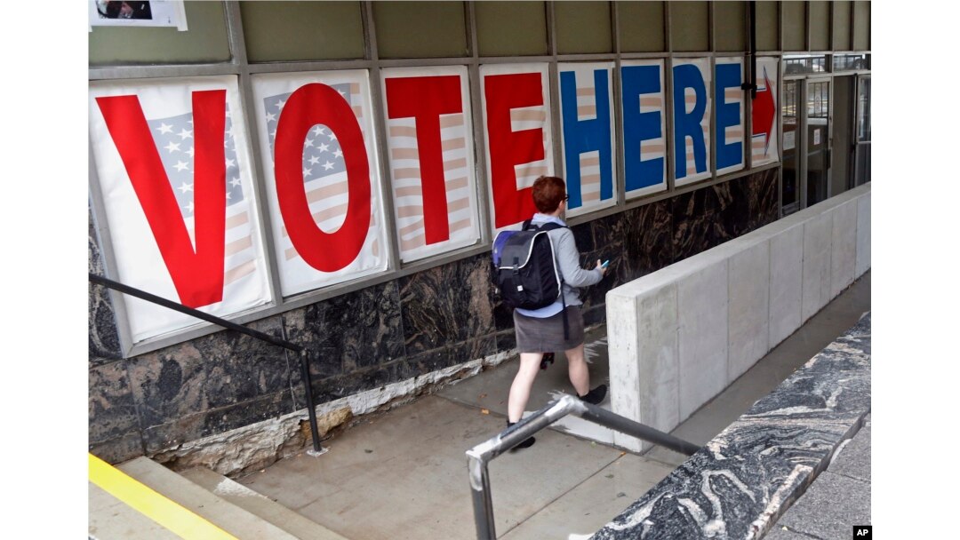 FILE - A voter passes a large sign before voting in Minneapolis.